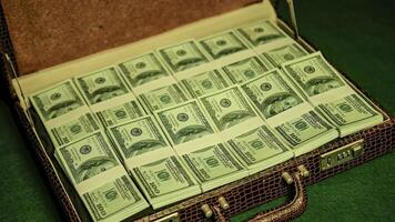 Man opens briefcase full of 100 dollars currency notes in a dimly lit nightclub photo