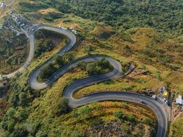 un aéreo perspectiva vitrinas el intrincado red de devanado carreteras serpenteante mediante el montañoso paisaje a el descanso de amanecer foto