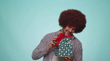 Smiling man presenting birthday gift box stretches out hands, offer wrapped present career bonus video