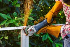 Worker grinding steel frame with handheld angle grinder. Grinding with sparks flying photo