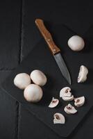 Sliced champignons on a board next to a knife photo