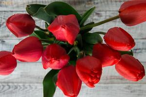 rojo tulipanes con hojas mentira en un de madera antecedentes foto