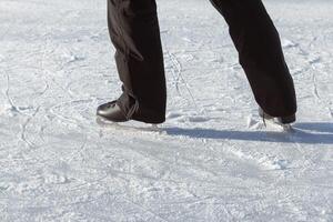 de los hombres piernas en negro patines de cerca en el pista a el momento de el empujar antes de Patinaje. activo invierno Días festivos foto