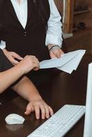 A woman and a man discuss business issues, consider documents. A man at a table with a computer, a woman stands next to him and shows a report photo