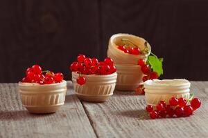 Bunches of red currants in waffle plates on a wooden table. Still life with berries filled with vitamins photo