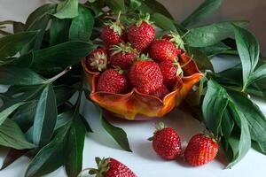 maduro rojo fresas baya en un naranja florero foto