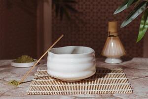 Tea ceremony from the matcha. Tyawan, tyasaku, tyasen on a stone table top among bamboo leaves photo