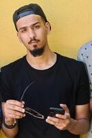 Close Up Portrait of Smiling Sudanese Teenager with Broad Smile, Chin, and Cap Using Smartphone photo