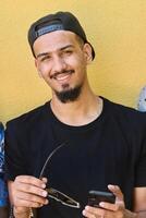 Close Up Portrait of Smiling Sudanese Teenager with Broad Smile, Chin, and Cap Using Smartphone photo