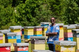 African American Teenager Exploring Small Beekeeping Businesses in Traditional Sudanese Attire amidst Nature photo