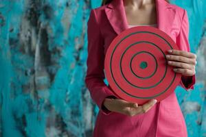 In a display of determination, the businesswoman holds a substantial dartboard, prepared to aim at the target with confidence and skill, Generated AI photo