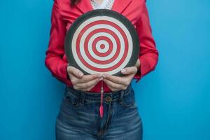 The businesswoman confidently holds a large dartboard, ready to take aim at the target with precision and determination, Generated AI photo