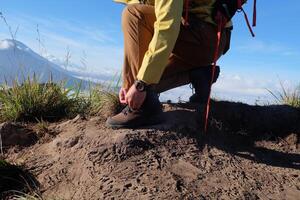 caminante atadura zapato en montaña pico preparando para aventuras con escénico ver foto