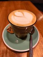 Latte with beautiful foam art and cookie on a cafe table, relaxing coffee time photo