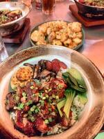 delicioso asiático arroz cuenco maceta de barro coronado con Cerdo lapciong, pollo y verduras foto