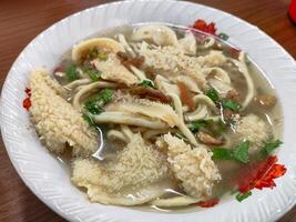 Mie Babat, Traditional Soup with Noodles and Fresh Herbs in a White Bowl photo