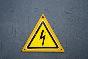 electricidad advertencia amarillo triángulo firmar en gris metal puerta foto