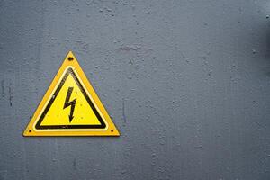 Electricity Warning Yellow Triangle Sign on Grey Metal Door photo