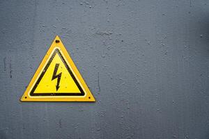 Electricity Warning Yellow Triangle Sign on Grey Metal Door photo