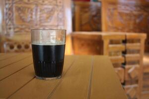 glass cup filled with black coffee on a brown table photo