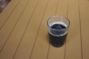 glass cup filled with black coffee on a brown table photo