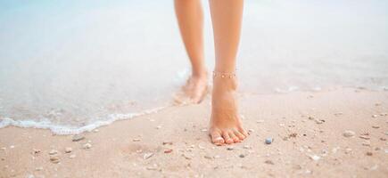 hembra piernas caminando a lo largo el playa descalzo, de cerca de el Perfecto bronceado piernas de un niña viniendo fuera de el agua después nadar. mujer relajante en vacaciones a el playa, verano vacaciones concepto foto