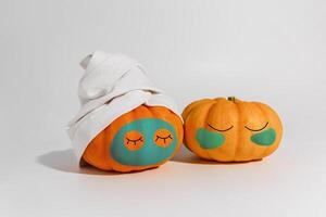 Pumpkin with facial mask and towel isolated on white background. Space for text mockup spa and Halloween concept photo