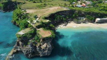 Aerial drone view of sandy beach with scenic rock and blue ocean in Bali video