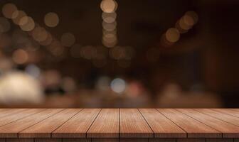 Empty wooden table top with lights bokeh on blur restaurant background photo