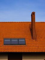 roof of a house made of red tiles with a chimney and attic photo