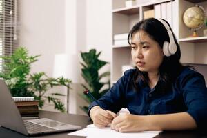 Happy student, studying for MBA exam, takes advantage of distance learning to attend school from home, balancing training and class. Woman studies book and research for online academy using laptop. photo