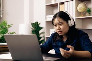 contento alumno, estudiando para MBA examen, toma ventaja de distancia aprendizaje a atender colegio desde hogar, equilibrio formación y clase. mujer estudios libro y investigación para en línea academia utilizando ordenador portátil. foto