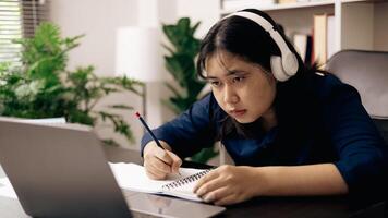 creative young student uses a laptop to complete online homework for college and university courses. Woman studies a book and conducts research for online academy using laptop in office. photo