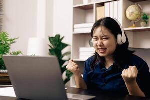 Happy student, studying for MBA exam, takes advantage of distance learning to attend school from home, balancing training and class. Woman studies book and research for online academy using laptop. photo