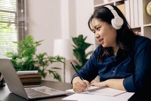 contento alumno, estudiando para MBA examen, toma ventaja de distancia aprendizaje a atender colegio desde hogar, equilibrio formación y clase. mujer estudios libro y investigación para en línea academia utilizando ordenador portátil. foto