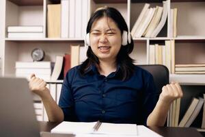 Happy student, studying for MBA exam, takes advantage of distance learning to attend school from home, balancing training and class. Woman studies book and research for online academy using laptop. photo