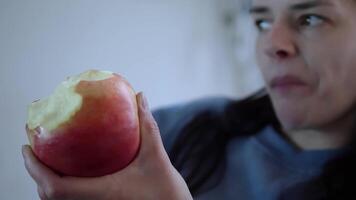 joven mujer disfruta el Fresco gusto de un manzana, masticación contentamente. manzana en mano, su disfrute es evidente. cada mordedura de el manzana refleja saludable, alegre vivo concepto sano comiendo video