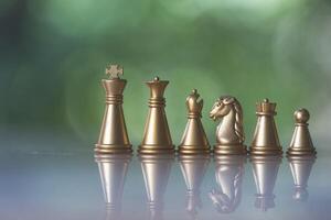 Sets of golden chess pieces on nature background, king, rook, bishop, queen, knight, and pawn. photo