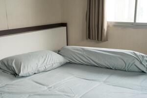 azul cama con uno almohadas y uno refuerzos siguiente a ventana. soledad foto