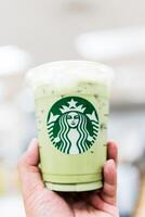 Bangkok, Thailand - May 29, 2024 Male hand holding Starbucks iced matcha green tea latte. photo