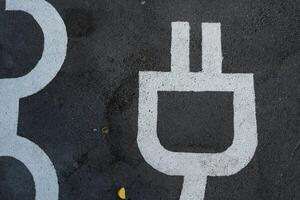 el símbolo para cargando el eléctrico vehículo en estacionamiento lugar. foto