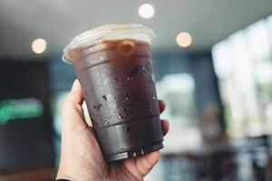 Someone hand holding a plastic cup of iced Americano photo