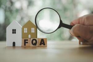 Man hand uses magnifying glass to find answer FAQ about home. Question and answer about housing problems photo