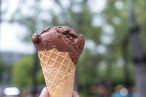 Hand holding an ice cream chocolate in waffle cone. Vacation and fun. photo
