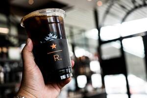 samut prakan, Tailandia - mayo 1, 2024 hombre participación con hielo negro café a a Starbucks reservar, mega bangnashopping centro comercial. foto