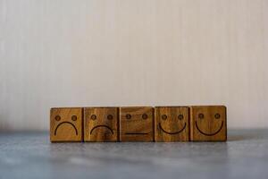 Satisfaction feedback in form of face emoticon on wood block photo