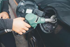 mano de un gas estación trabajador llena arriba el coche tanque. el gastos de petróleo. foto