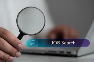 A man hold a magnifier to find job with search icon bar, seeking into right job. photo