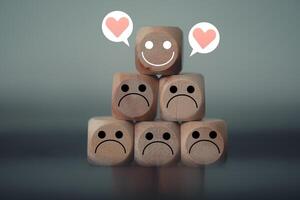 Happy face with heart icons among many sad emotions on wooden blocks. Happy leader among negative team. photo