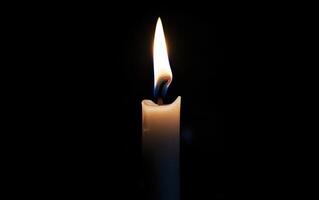 Burning white candle on black background. Close-up photo. With copy space. Image for memory of events and people photo